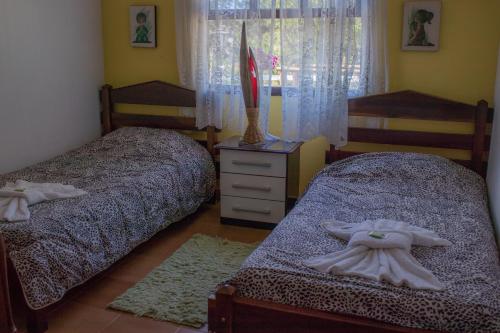 a bedroom with two beds and a dresser and a window at Pousada Sonho Meu in Itanhandu