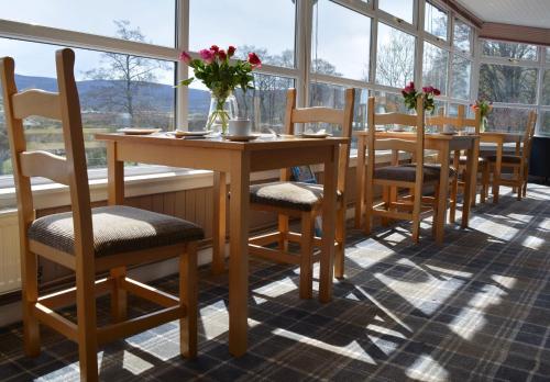 een tafel en stoelen in een kamer met ramen bij Feughside in Strachan