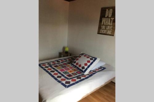 a small bedroom with a bed with a quilt on it at Votre appartement à 200m de la plage in Ouistreham