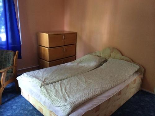 an unmade bed in a bedroom with a dresser at Malomtavi Vendégház in Tapolca