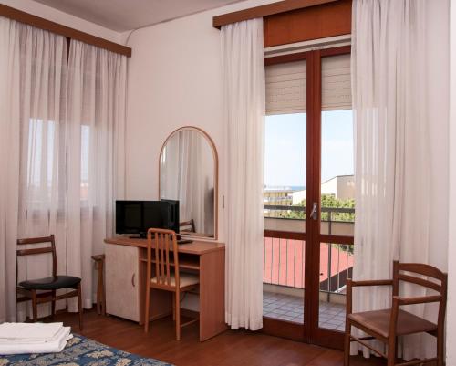 um quarto com uma secretária com um espelho e uma varanda em Hotel Rugantino em Cesenatico