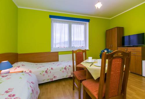 a room with two beds and a table and a television at Willa Anna in Międzyzdroje