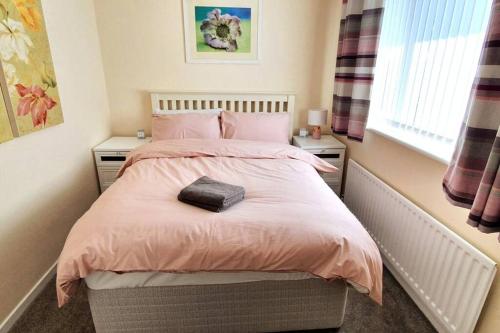 a bedroom with a bed with pink bedding and a window at Stamford - Entire 1 bed cosy home. in Stamford