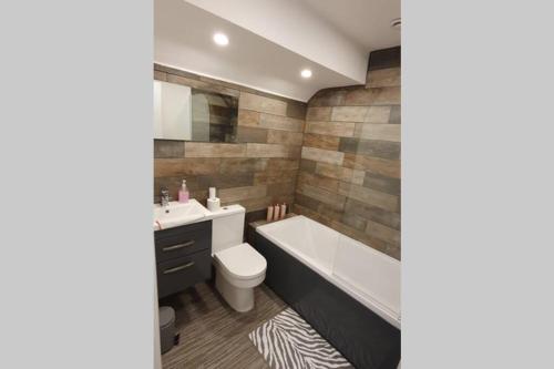 a bathroom with a tub and a toilet and a sink at Stamford Guest House in Stamford