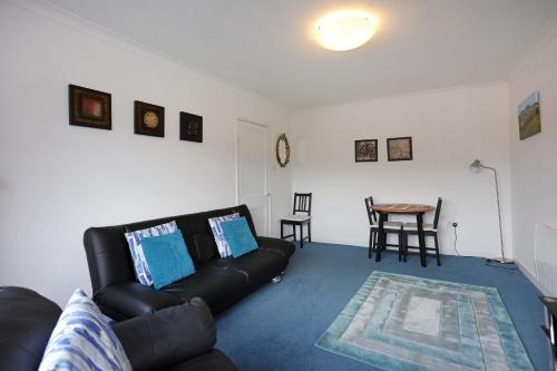 a living room with a black leather couch and a table at Ideal Central Edinburgh location with free on-site private parking in Edinburgh