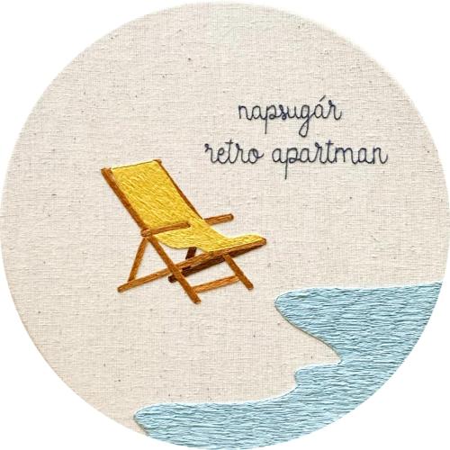 a yellow chair sitting on the beach next to the water at Napsugár Retro Apartman in Gárdony