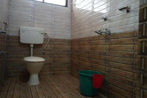 a bathroom with a toilet and a green bucket at SANGEETHA TOURIST HOME in Trivandrum