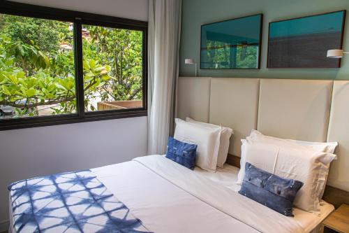 a bedroom with a bed with two pillows and a window at Wyndham Ilhabela Casa Di Sirena in Ilhabela