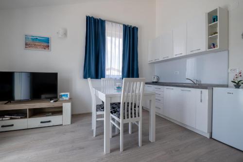 a kitchen with a white table and chairs and a tv at Apartmani MATE Neum in Neum