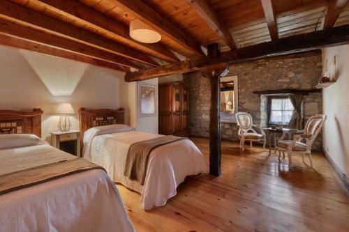 a bedroom with two beds and a stone wall at Casa Magdalena: mar y montaña in Adino