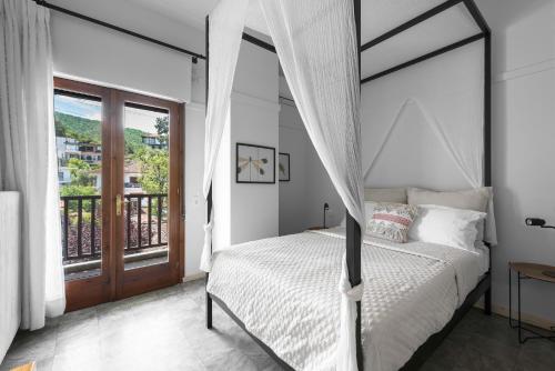 a bedroom with a canopy bed and a balcony at Kalokerino in Olympiada