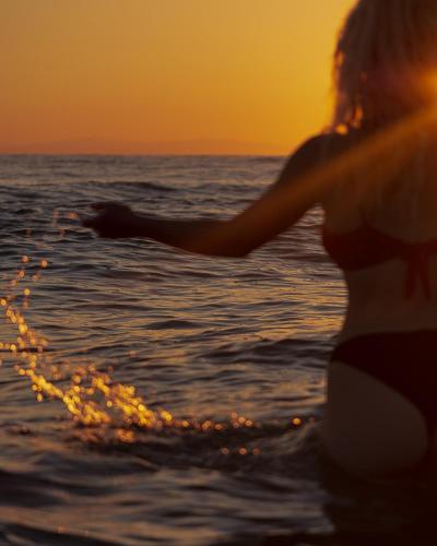 a woman in the water at the beach at sunset at Vila Aleka in Nei Poroi