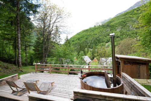 eine Holzterrasse mit einer Badewanne und 2 Stühlen in der Unterkunft Camp Korita in Soča