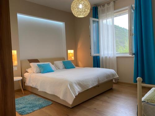 ein Schlafzimmer mit einem Bett mit blauen Kissen und einem Fenster in der Unterkunft Villa Betty Dubrovnik in Gruda
