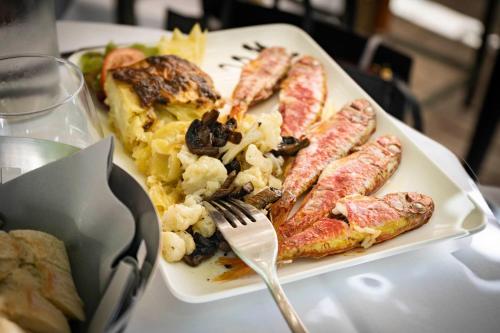 a plate of breakfast food with a fork on a table at Monsieur Miot Concept Hotel - Bastia centre in Bastia