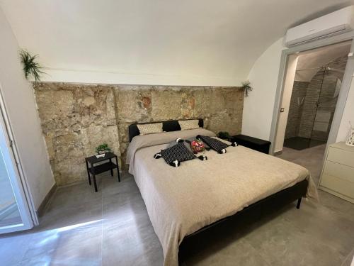 a bedroom with two beds and a stone wall at Tufoletto Apartment in Palermo