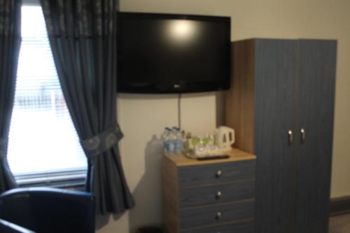 a bedroom with a dresser and a flat screen tv at Kings Boutique Hotel in Blackpool