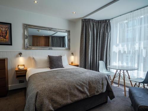 a bedroom with a bed and a table and a mirror at Carlton Hotel in Ilfracombe