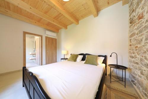 a bedroom with a large white bed and a stone wall at Villa Mira with a heated pool and a sea view in Božava