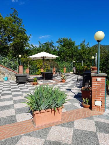 a patio with benches and an umbrella and plants at Bed&Breakfast Bella Vita in Bracco
