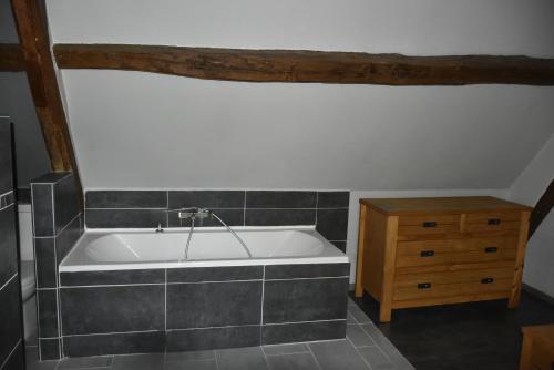 La salle de bains est pourvue d'une baignoire et d'une commode en bois. dans l'établissement Gite du Pont Saint-Céneri-Le-Gérei dans les Alpes Mancelles, à Saint-Céneri-le-Gérei