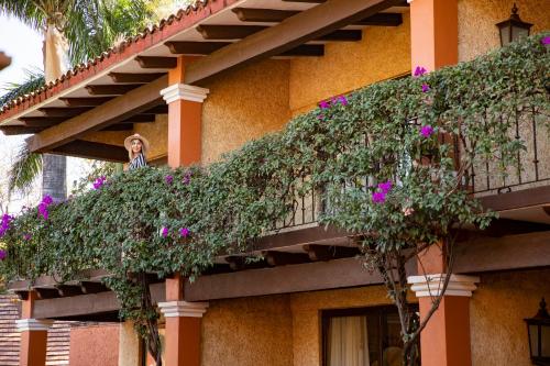 a woman standing on the balcony of a building with flowers at Hosteria Las Quintas Hotel Restaurante Bar in Cuernavaca