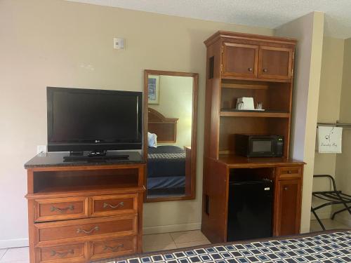 a bedroom with a television and a dresser with a mirror at Highland Inn Denham Springs Baton Rouge East in Denham Springs