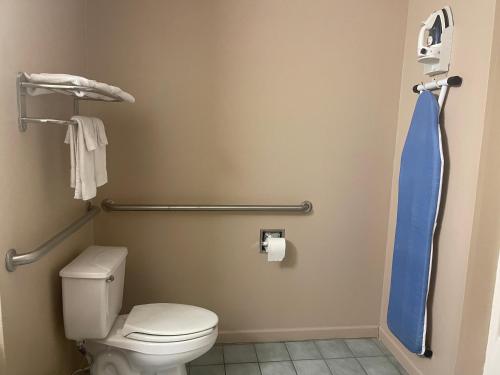 a bathroom with a toilet and a blue shower curtain at Highland Inn Denham Springs Baton Rouge East in Denham Springs