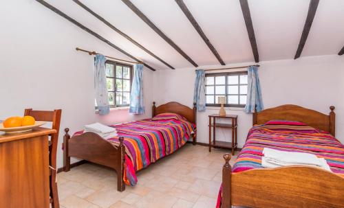 a bedroom with two beds and a table and two windows at Quinta de São Pedro in Sobreda