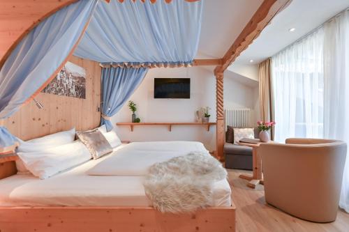 a bedroom with a large bed with a blue drape at Hotel Alpenstuben in Hohenschwangau