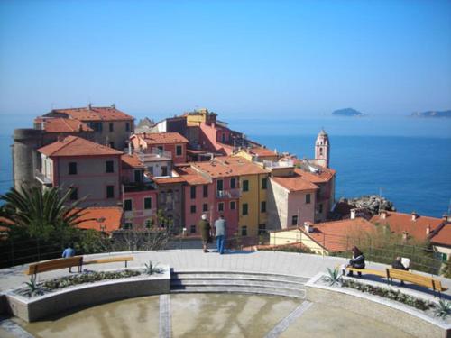 a group of people sitting on benches in front of a city at La casetta del Marinaio in Tellaro