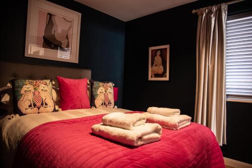 a bedroom with a large bed with red blankets and pillows at The Garden Apartment in Deal