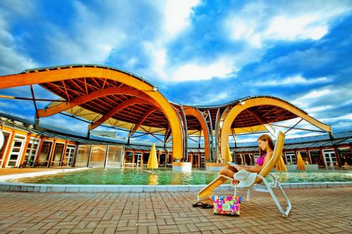 a woman sitting in a chair in front of a pool at Hunguest Bük - ex Répce és Répce Gold in Bük