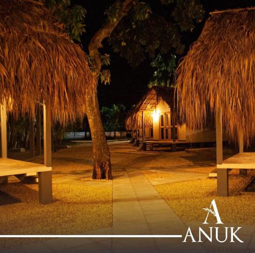 a night view of a building with a tree and benches at Anuk Glamping in San Bernardo del Viento