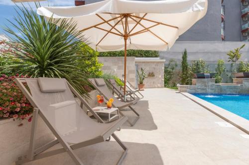 a group of chairs and an umbrella next to a pool at Boutique Hotel Momentum by Aycon in Budva