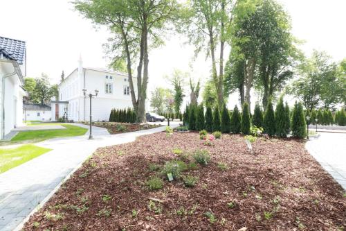 a garden with flowers and trees on a sidewalk at Gasthaus am Henriettenhof in Grömitz