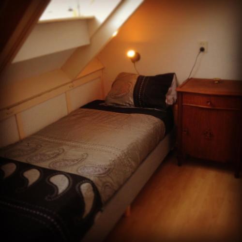 um pequeno quarto com uma cama e uma cómoda em Huisje Stockholm op Terschelling em West-Terschelling