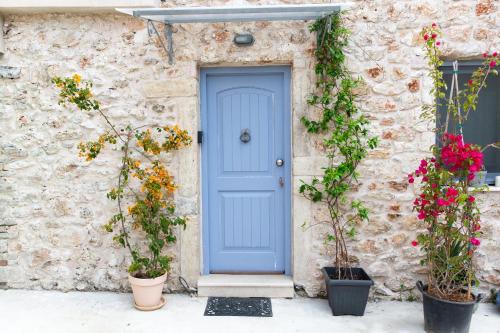 a blue door on the side of a stone building with flowers at Luxurious bungalow in Ipsos beach in Ýpsos
