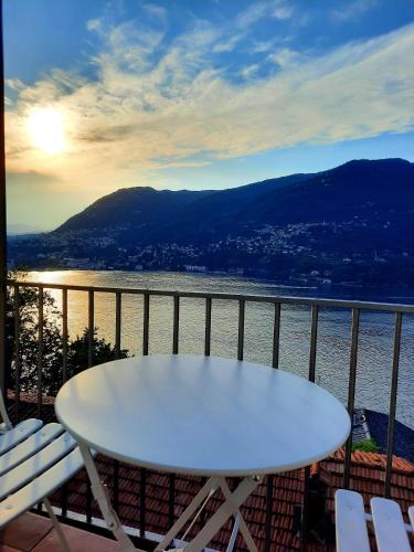 a white table on a balcony with a view of the water at Le Luci sul Lago di Como in Blevio