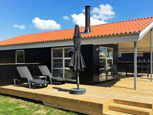 an umbrella sitting on a deck next to a house at 6 person holiday home in R nde in Rønde