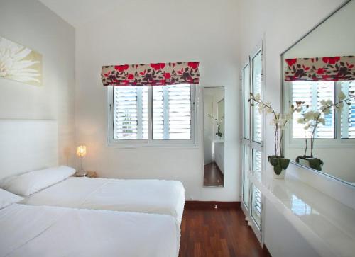 ein weißes Schlafzimmer mit 2 Betten und 2 Fenstern in der Unterkunft Villa Kos 19 in Protaras