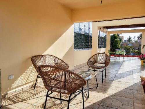 a patio with three chairs and a glass table at Hostal en El Centro LaKiwa in Mazatlán