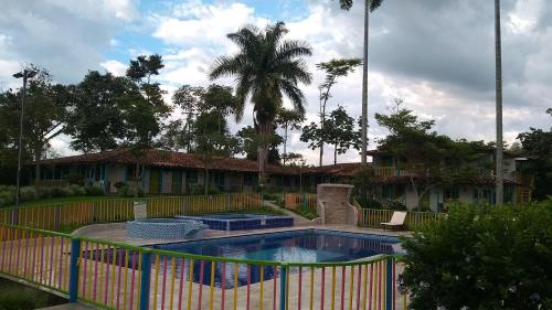 a swimming pool with a fence and a palm tree at Finca Hotel los Nogales in Quimbaya