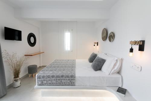 a white bedroom with a bed and a tv at Iades Studios & Apartments in Agia Anna Naxos