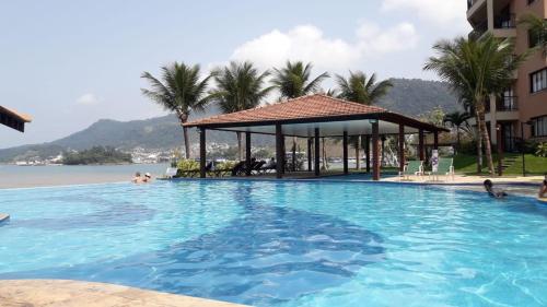 ein großer Pool mit Pavillon neben dem Wasser in der Unterkunft Angra dos Reis - Porto Bali - SUÍTE no Porto Bali Resort in Angra dos Reis