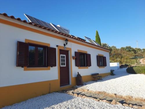 una casa con finestre con persiane marroni e un gatto seduto all'esterno di Lugar d´vagar, Vale Serrão, Castelo de Vide a Castelo de Vide