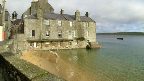 an old building on the shore of a body of water at Queens Hotel in Lerwick