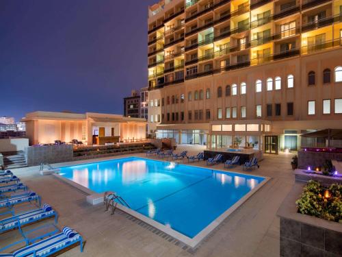 a swimming pool in front of a building at night at Treffen House Doha - Souq Waqif and next to Msheireb Metro Station in Doha