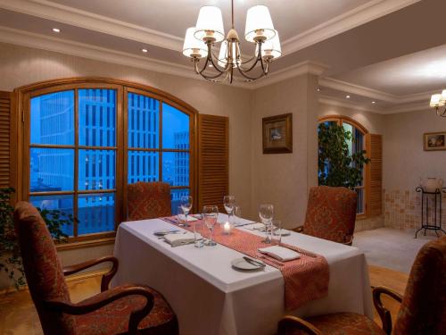 a dining room with a table and chairs and windows at Treffen House Doha - Souq Waqif and next to Msheireb Metro Station in Doha