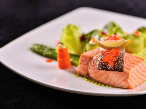 a plate of food with salmon and vegetables on a table at Treffen House Doha - Souq Waqif and next to Msheireb Metro Station in Doha